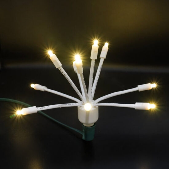 Warm White LED Glitzer (Star Cluster) C9 light bulb with multiple glowing arms and a white body on a green wire socket. C9 LED Glitzer Warm White