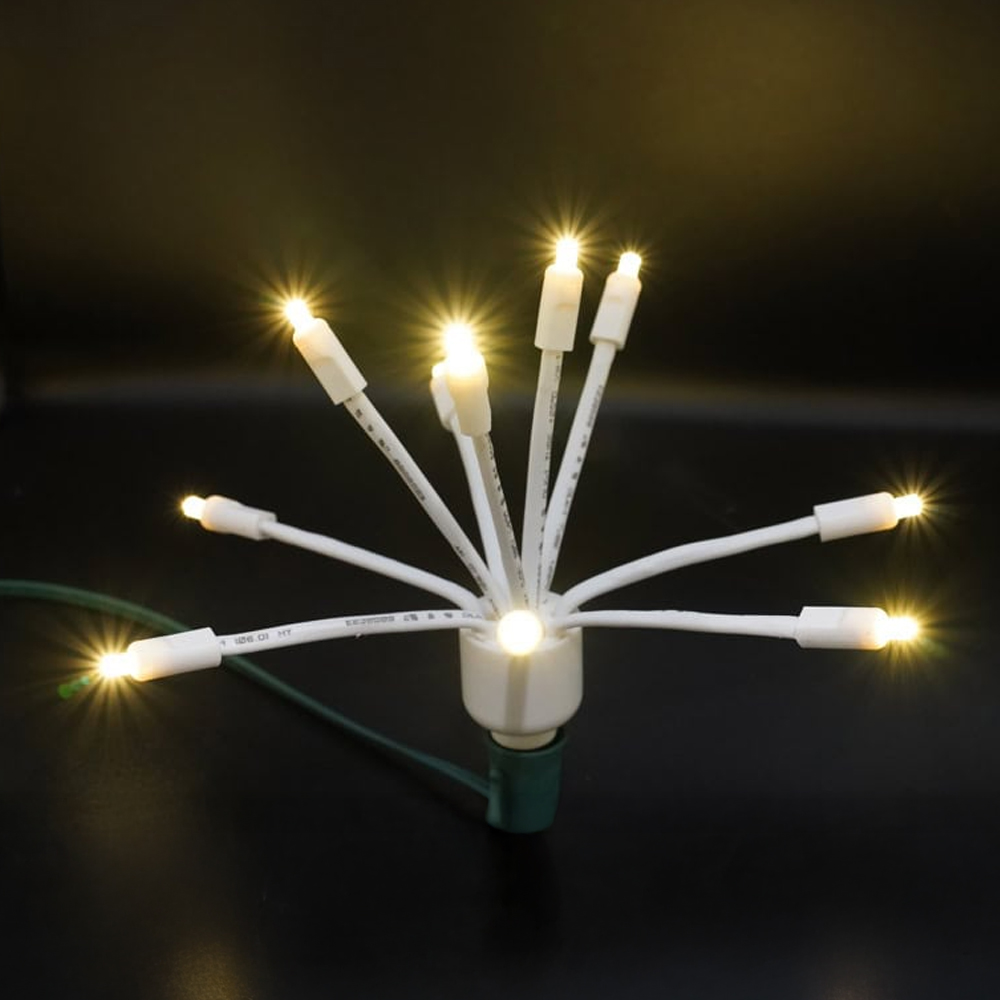 Warm White LED Glitzer (Star Cluster) C9 light bulb with multiple glowing arms and a white body on a green wire socket. C9 LED Glitzer Warm White
