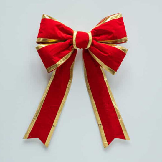 A traditional velvet bow accent piece, featuring a thick, rich red color and structured gold piping.
