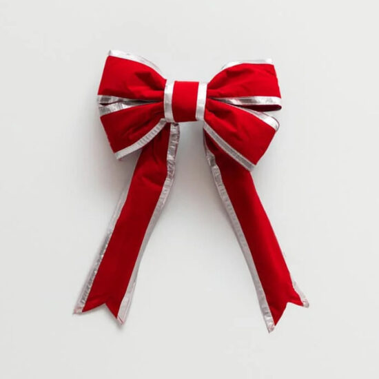 A large, festive red velvet bow decorated with thick silver metallic trim along all edges and long tails.