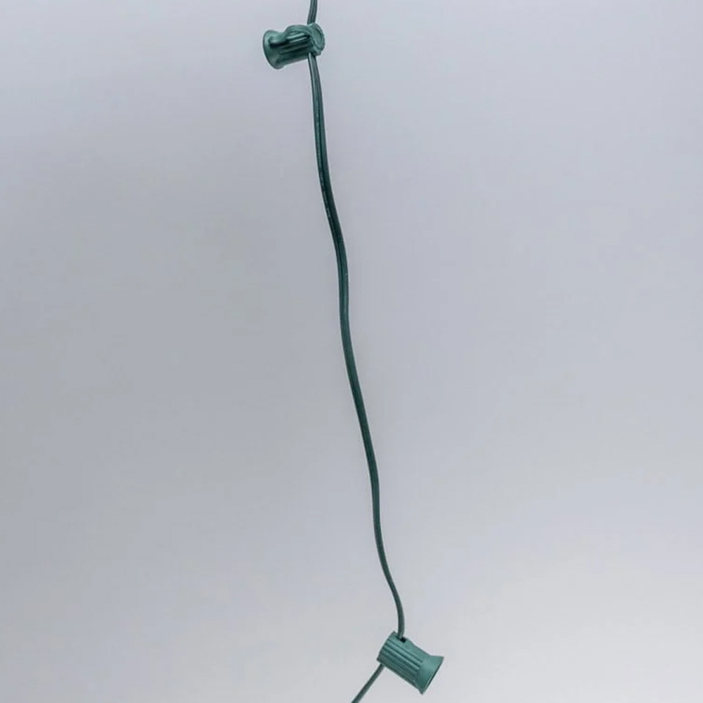 Close-up of bulk C7 light string wire with green sockets spaced 12 inches apart on a dark green wire. C7 Spool 12" Spacing Green 1000' Spool