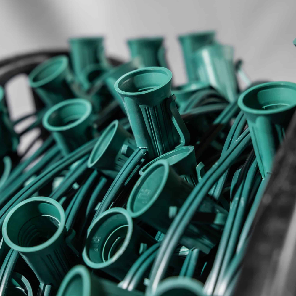 Bulk spool of C7 light stringer wire with green sockets and wire, shown tightly packed in a container. C7 Stringer 12" Spacing Green 100' Spool