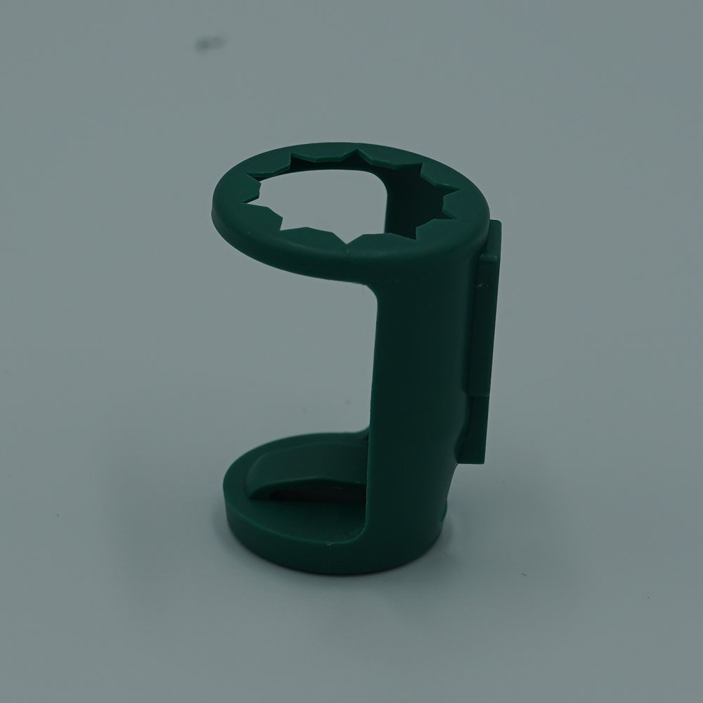 A small, green accessory clip designed for decorative lighting, with a circular, toothed slot for securing a bulb or cord.