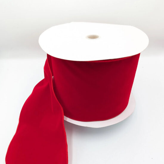 Large spool of wide, rich red velvet ribbon with a white cardboard core, unrolling onto a white background. Large spool of wide, rich red velvet ribbon with a white cardboard core, unrolling onto a white background.